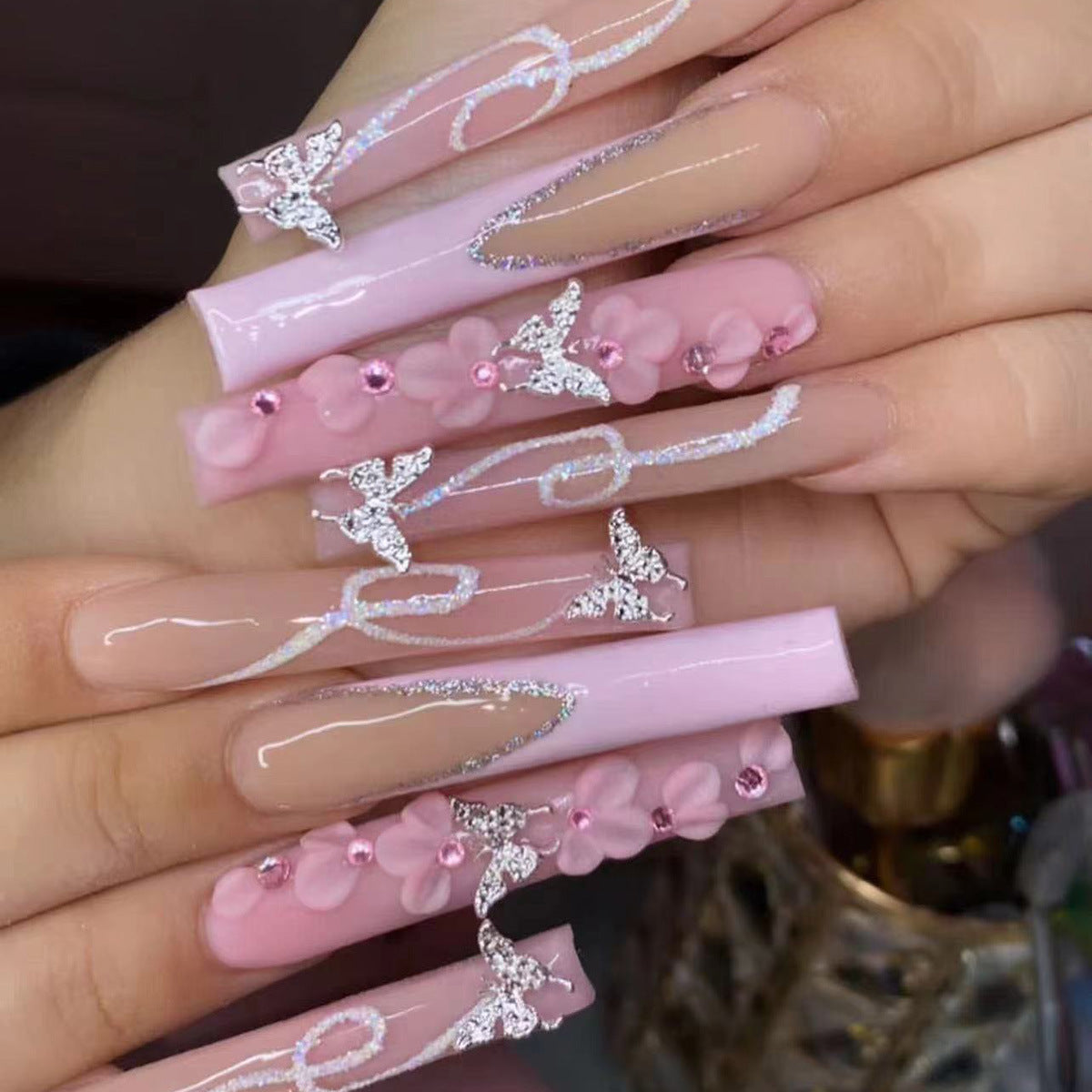 Faux ongles pailletés à porter avec des diamants en forme de fleur rose dans le nail art