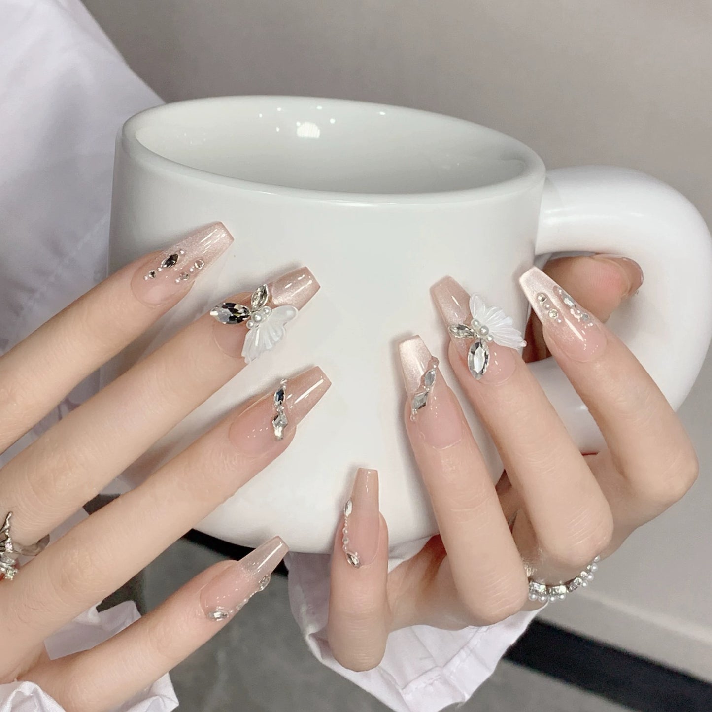 Nail art fait main avec un papillon, une fée et un chat portant un diamant