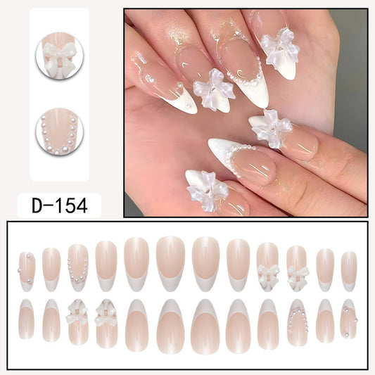 Faux ongles pointus couleur chair avec nœud en perles et nail art nude